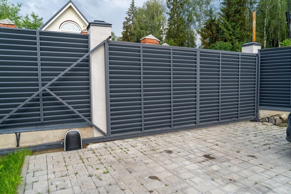 Portail Coulissant Automatique Moderne Gris Anthracite Portail coulissant motorisé gris anthracite à lames persiennes pour entrée de maison sécurisée.