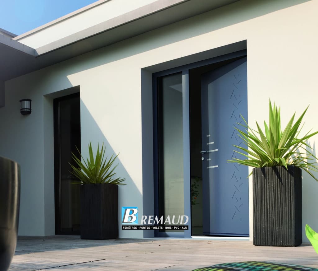 Porte d'entrée moderne Bremaud : menuiserie PVC et ALU Porte d'entrée grise moderne Bremaud ouverte sur une terrasse en bois avec grandes plantes et mur blanc épuré.