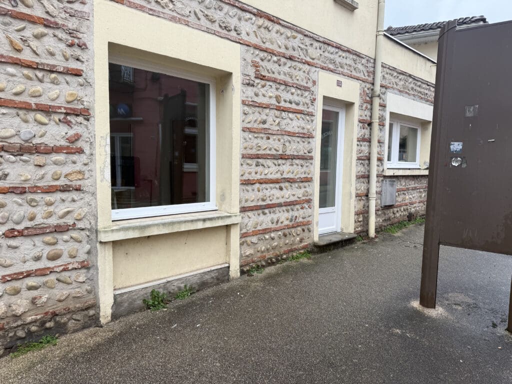 Façade en galets et briques avec fenêtre blanche et porte numéro 113.